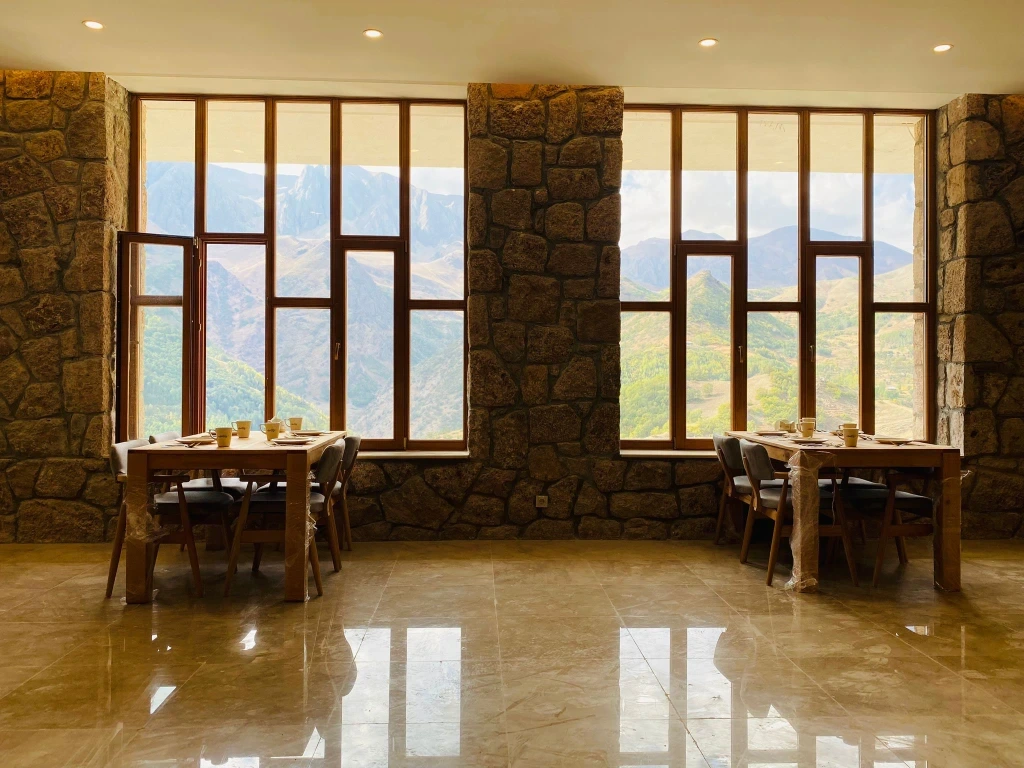 Taş duvarlı, ahşap masalı, dağ manzaralı restoran
