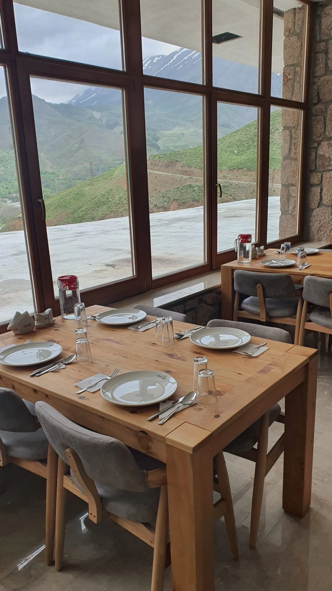 Büyük pencerelerin önünde kurulmuş restoran masaları