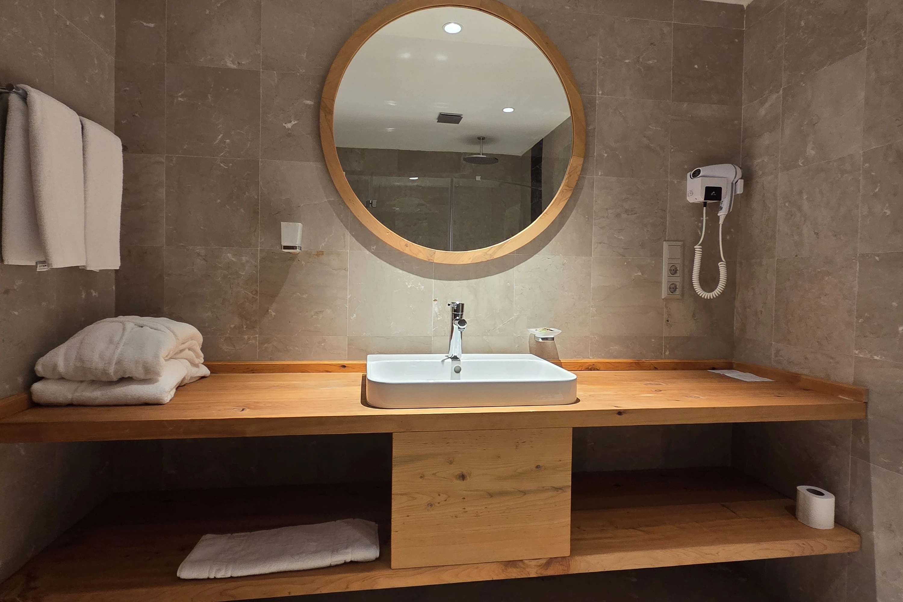 Yuvarlak aynalı ve ahşap lavabo tezgâhlı banyo