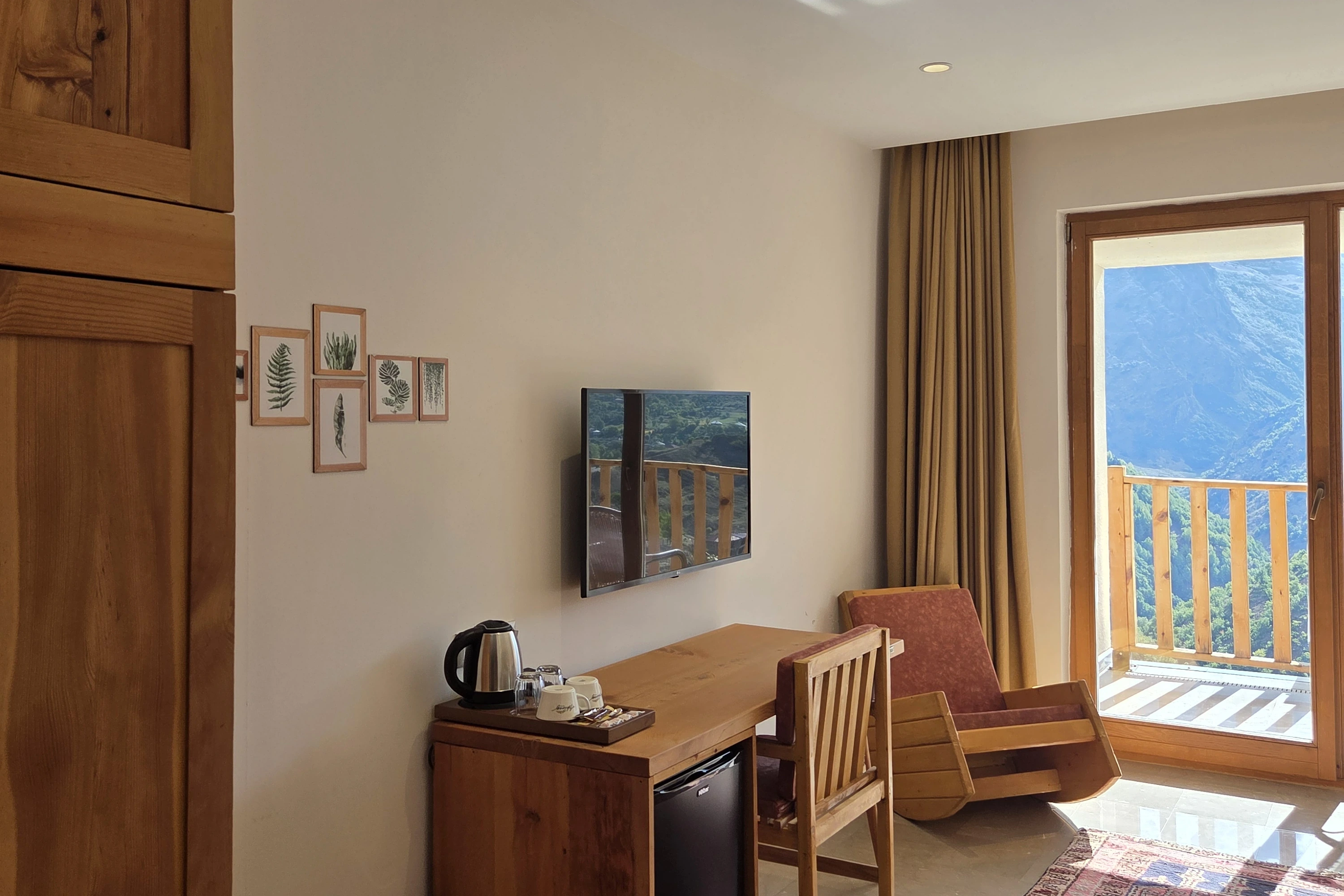 Süitte balkon kapısının yanında çalışma masası, televizyon ve koltuk